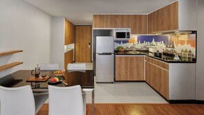 Une cuisine moderne avec des meubles en bois, un réfrigérateur blanc, un four à micro-ondes et un coin repas comprenant une table et des chaises.