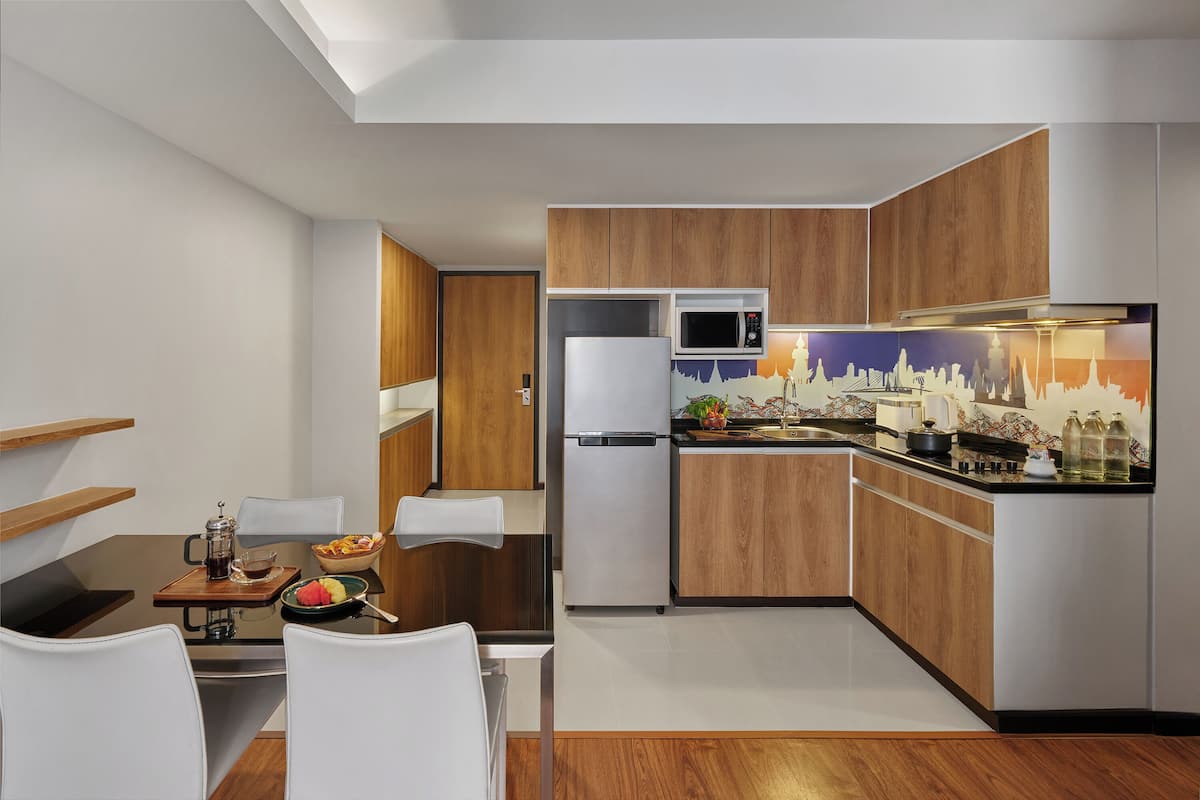 Une cuisine moderne avec des meubles en bois, un réfrigérateur blanc, un four à micro-ondes et un coin repas comprenant une table et des chaises.
