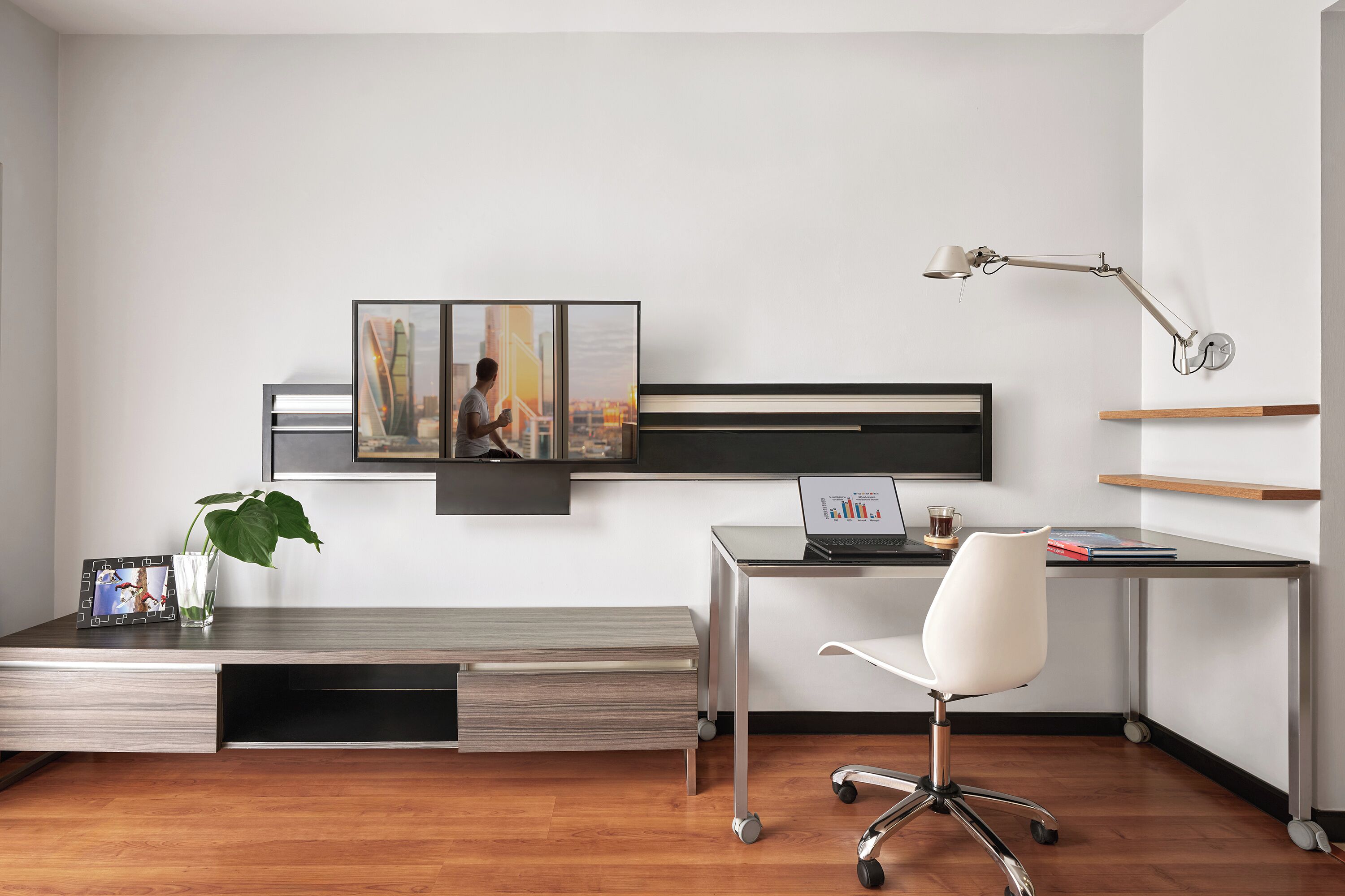 Un espacio de oficina moderno con escritorio, silla, lámpara y una obra de arte en la pared.