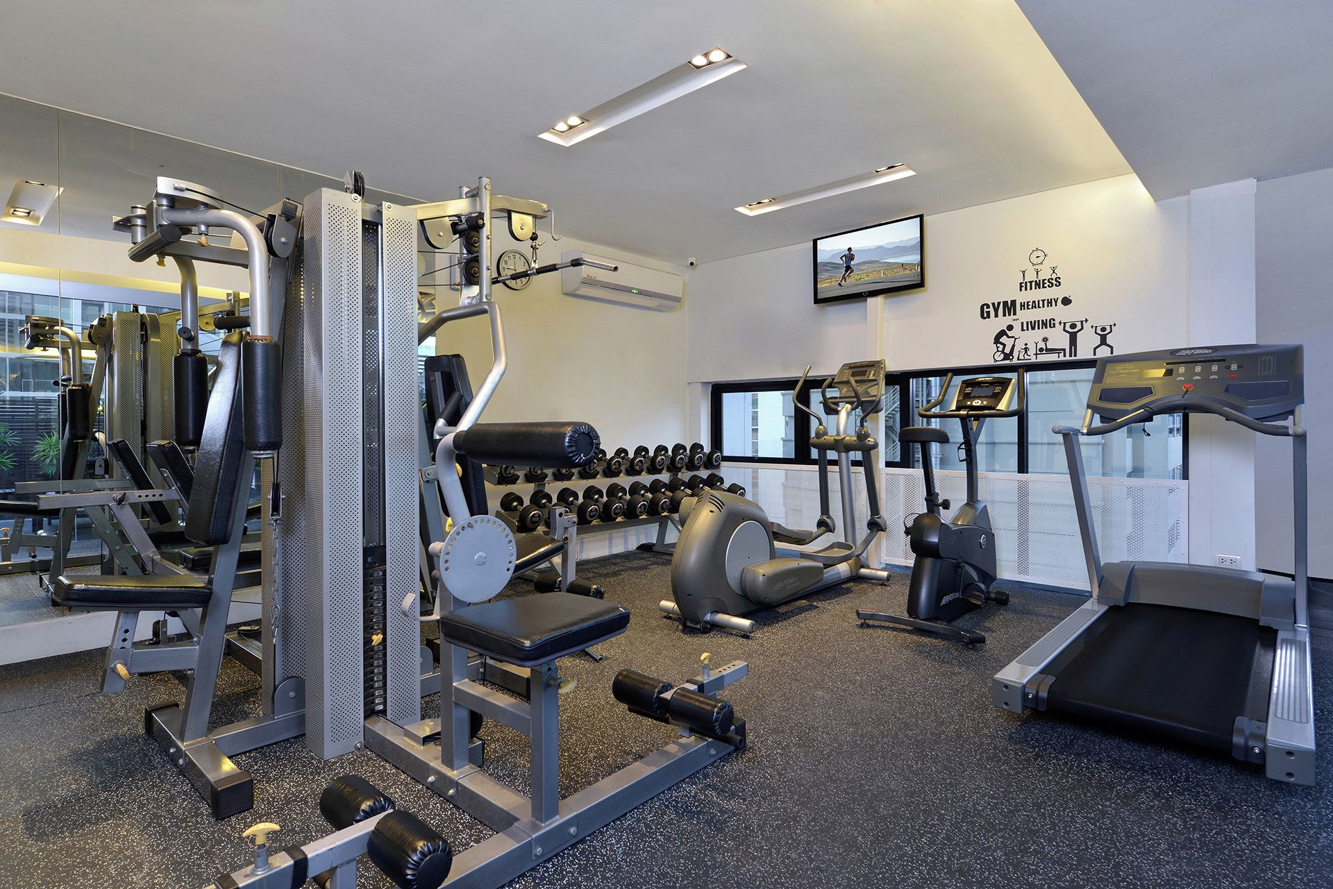 Ein Fitnessstudio mit unterschiedlichen Trainingsgeräten, Laufbändern und Kurzhanteln.
