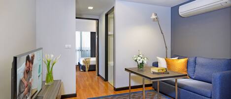 A modern living room with a flat-screen TV, a sofa, a coffee table, and a decorative vase.
