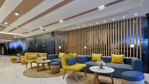 Een moderne lobby met een zithoek, bijzettafeltjes en een decoratieve wand.