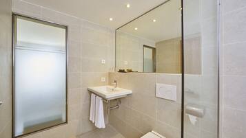 A modern bathroom with a glass shower enclosure, a sink with a towel, and a toilet.