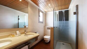 Een moderne badkamer met een grote spiegel, twee wastafels, een toilet en een douchecabine met glazen wanden.