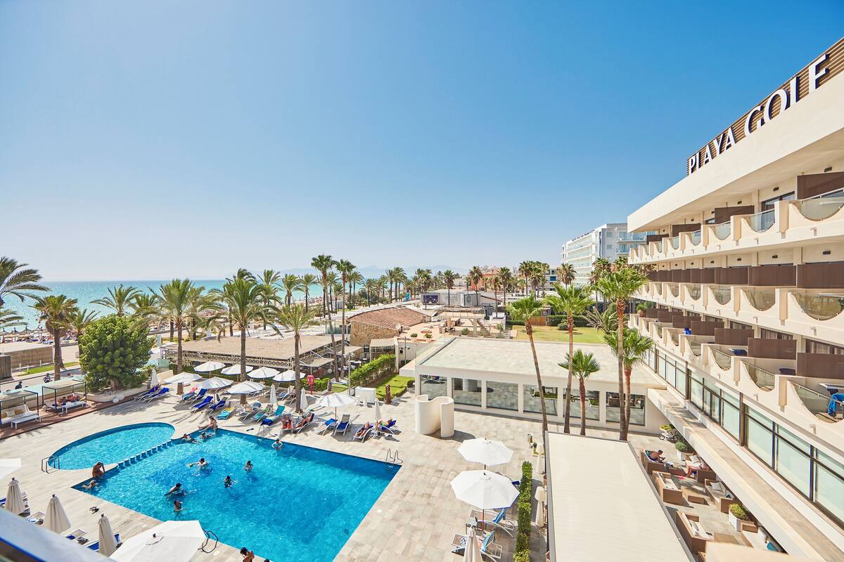 Un hôtel doté d’une piscine, de palmiers et offrant une vue sur l’océan.