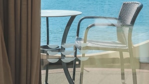 Un balcón con mesa y sillas, con vistas a una masa de agua.