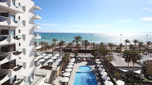 Un hotel con piscina, palmeras y vista al océano.