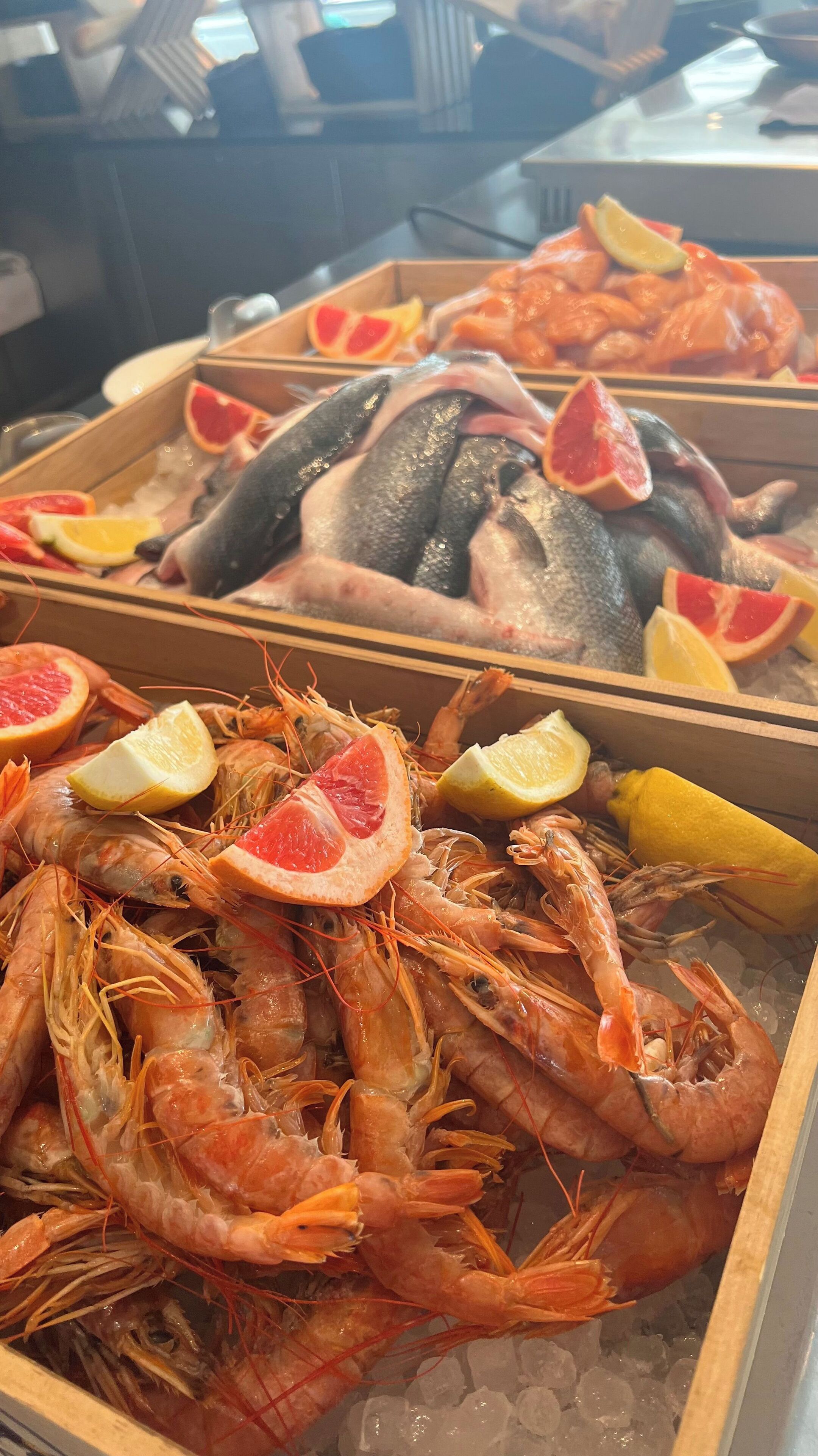 Una exhibición de mariscos con camarones, pescado y rodajas de cítricos.