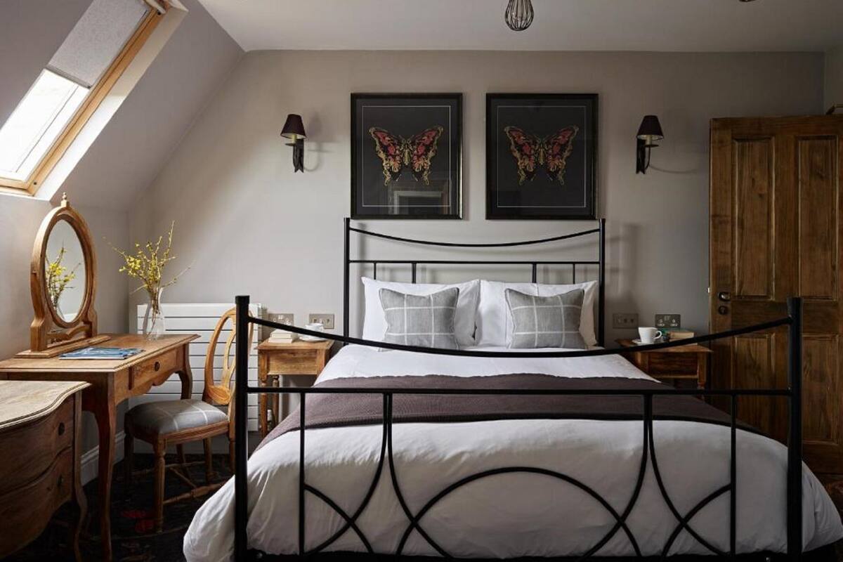 Une chambre à coucher comprenant un lit, un bureau, une chaise, une armoire en bois et deux lampes fixées au mur.