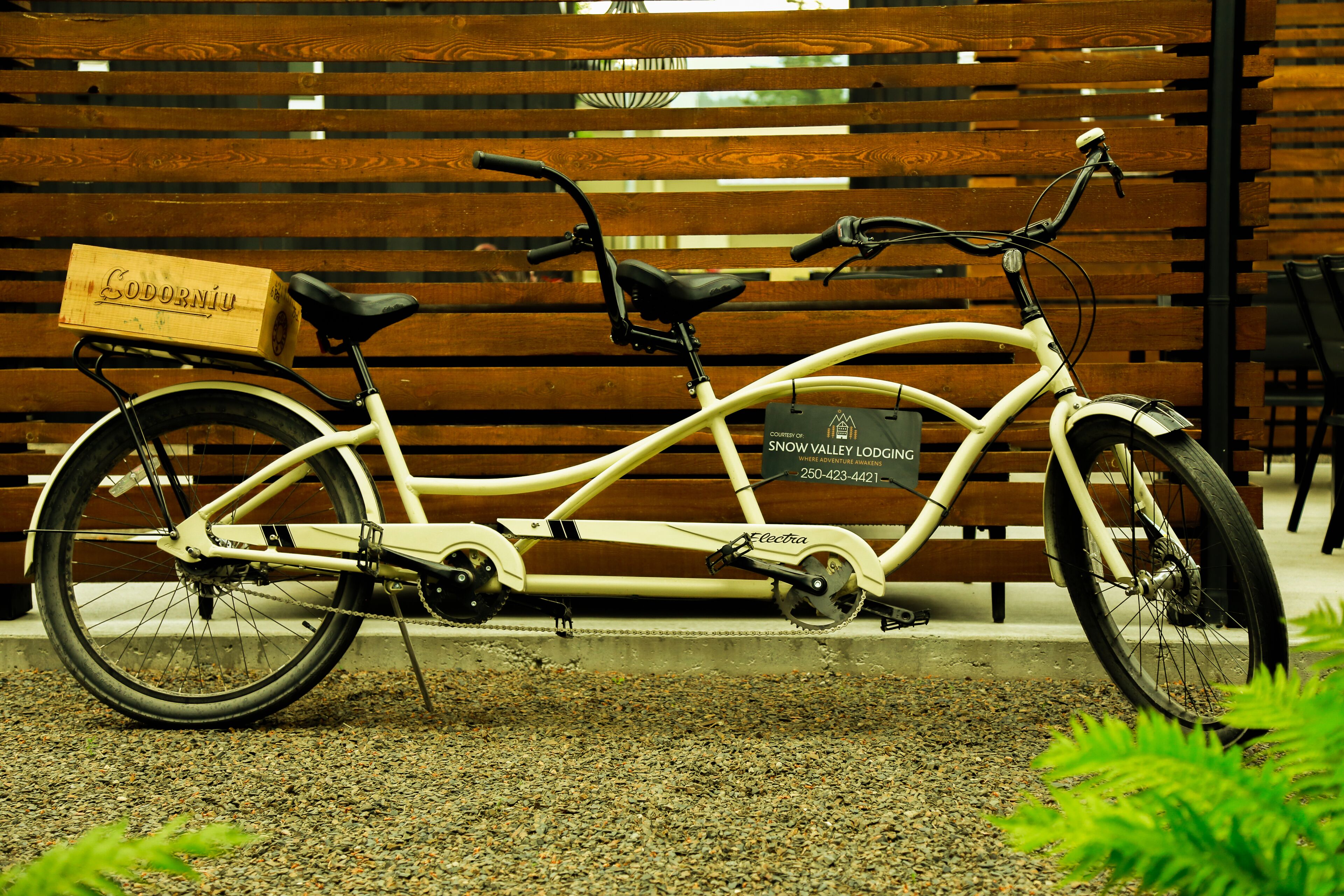 A stationary bicycle with a wooden box labeled "Codorniu" and a plaque that reads "Snow Valley Lodge."
