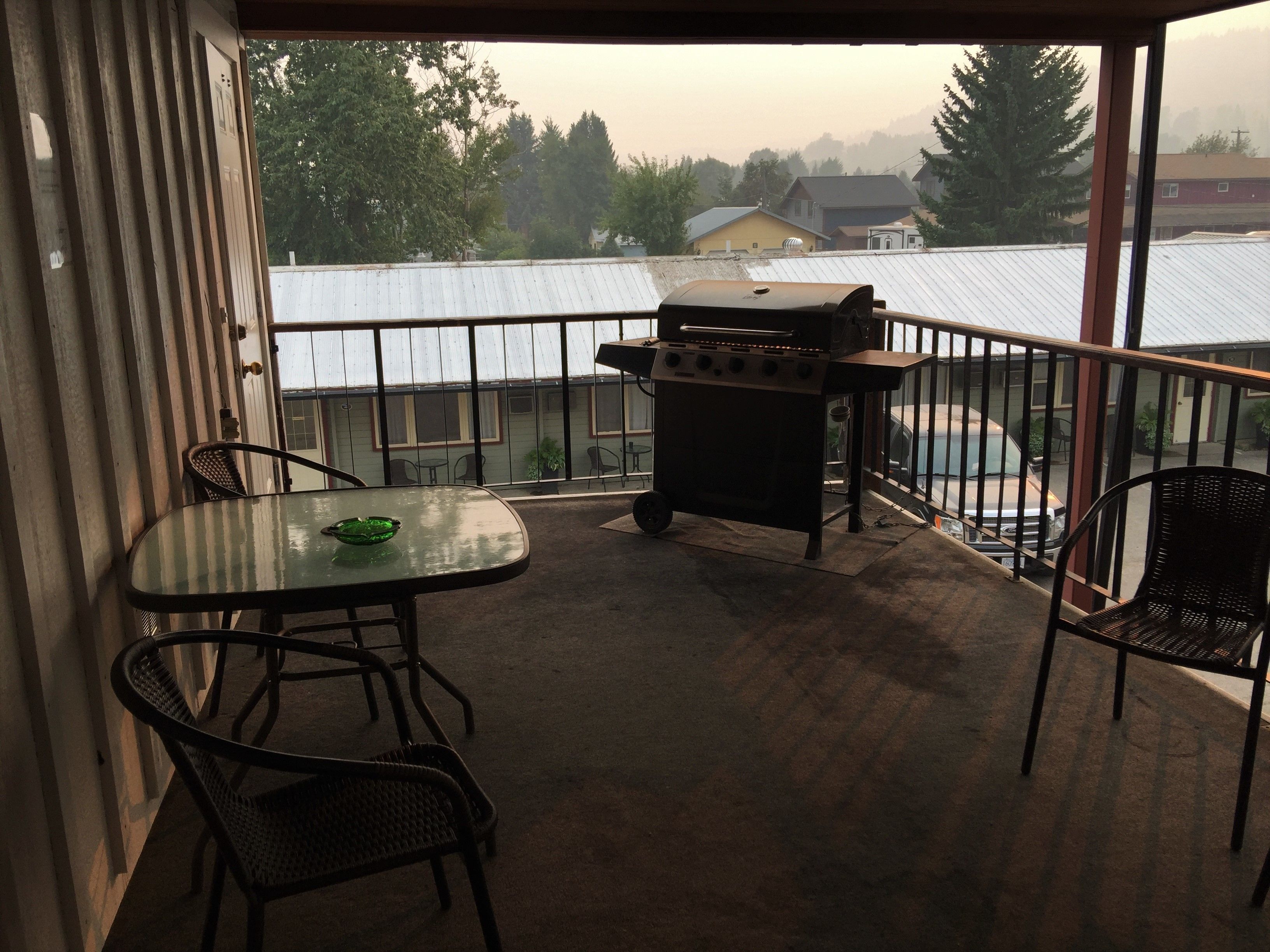 Un balcon avec un barbecue, une table et des chaises.