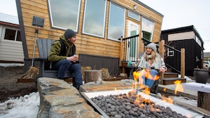 A wooden cabin with a fire pit in front. - Snow Valley Lodging (Fernie)