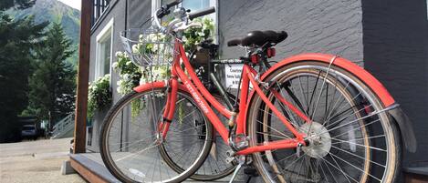 A red bicycle parked on a wooden platform in front of a building with a mountain view.