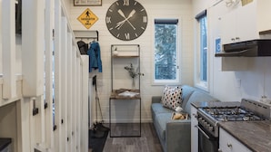 A compact kitchen with a stove, a clock, and a window. - Snow Valley Lodging (Fernie)