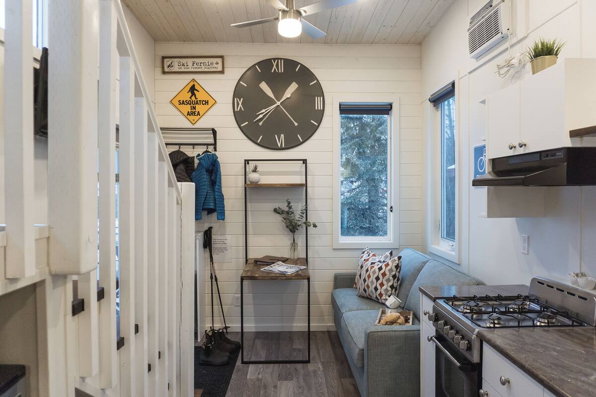 A compact kitchen with a stove, a clock, and a window.
