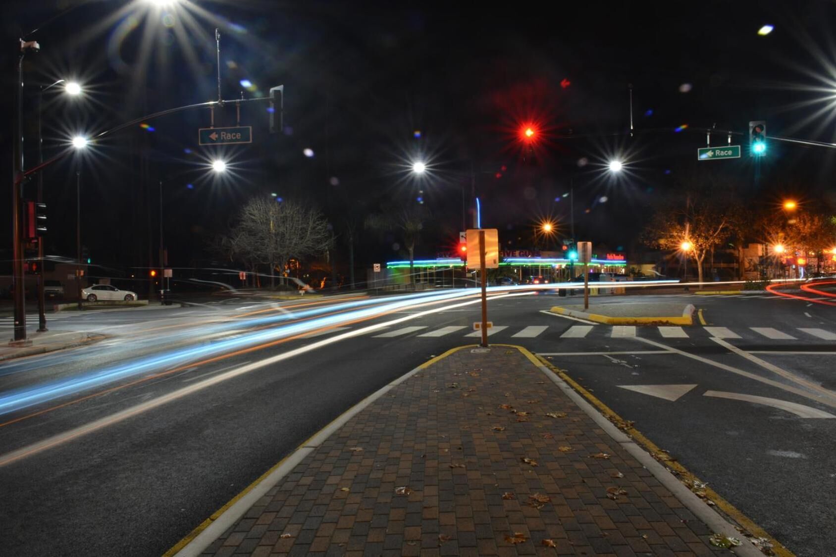 A nighttime intersection with traffic lights and road markings.