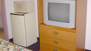 A compact room with a wooden cabinet containing a television and a small refrigerator.