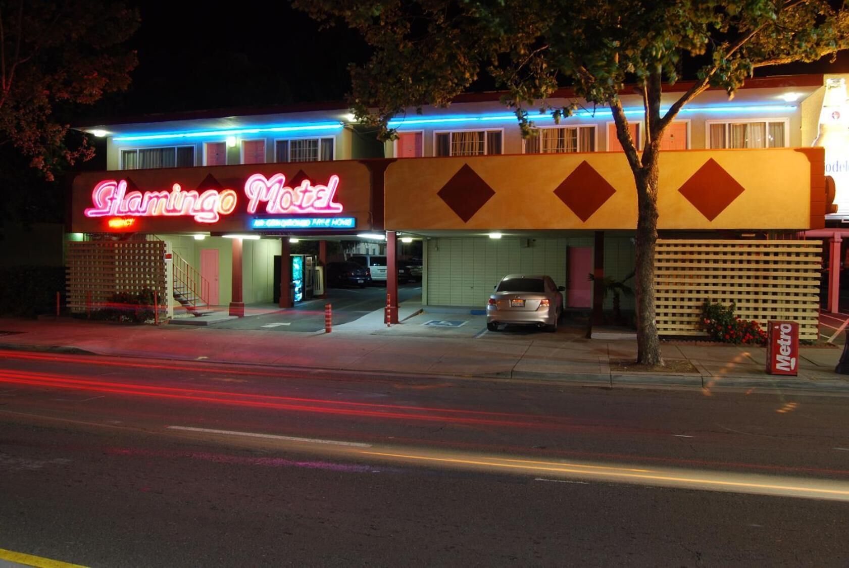 A motel with a neon sign, a parking lot, and a Metro sign.