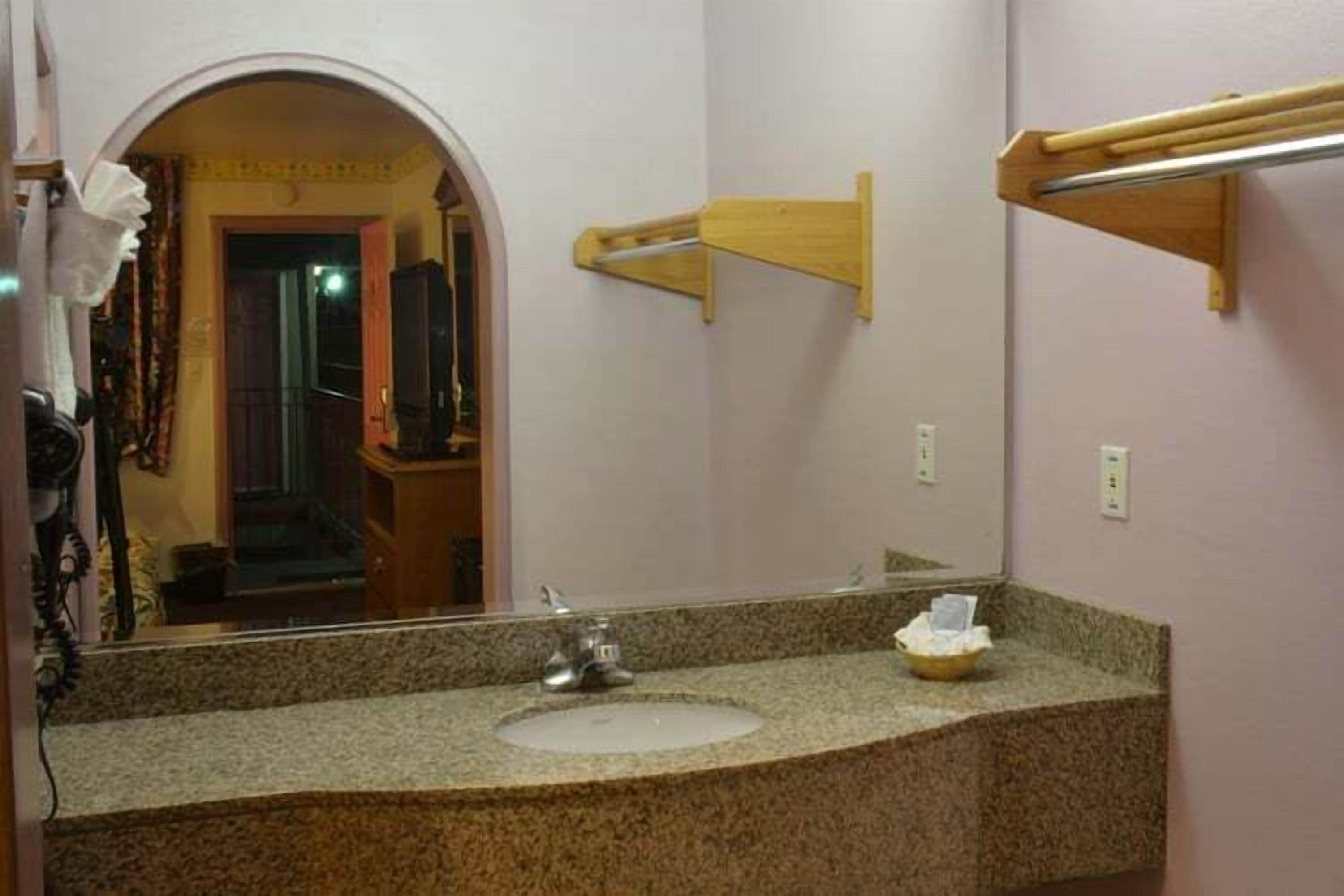 Un baño con encimera de granito, un lavabo, un espejo y un perchero de madera.