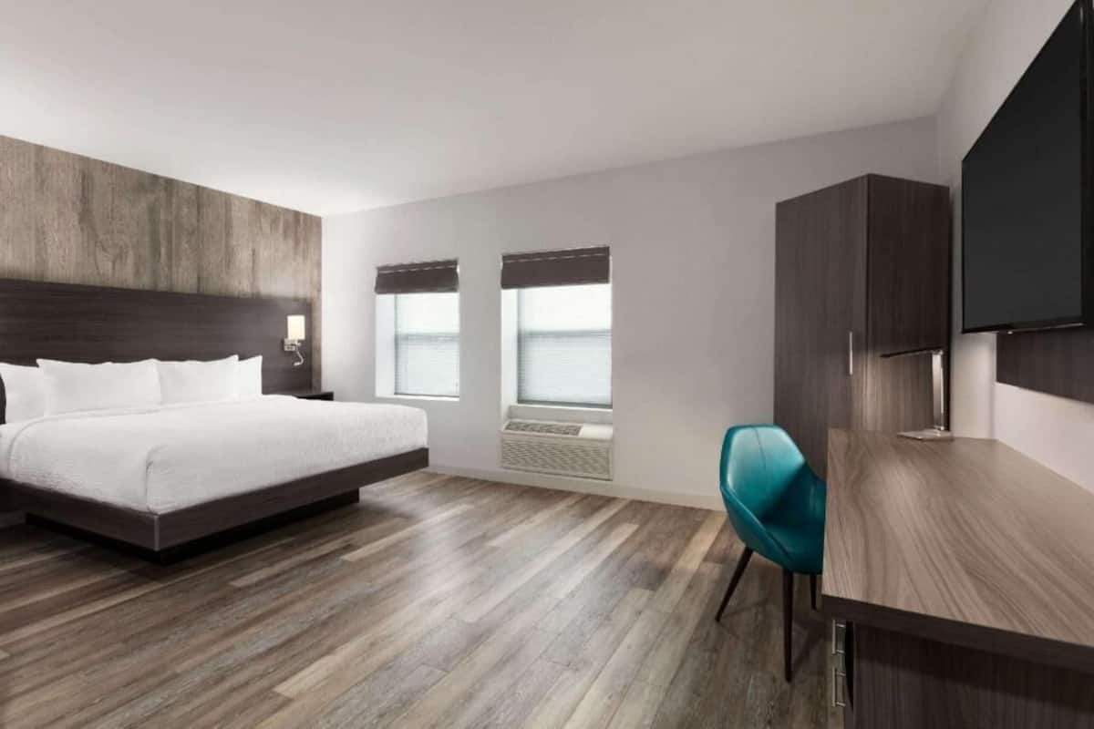 Ett modernt hotellrum med en stor säng, ett skrivbord, en stol och en TV.
