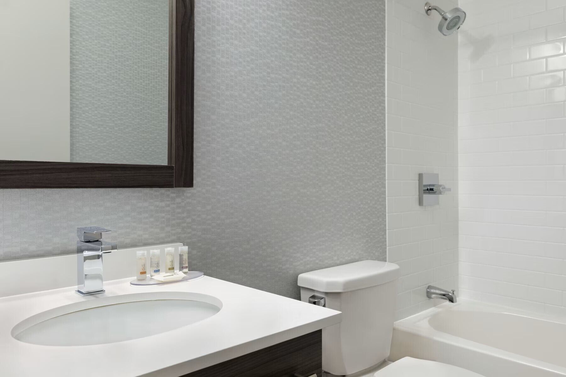 Een moderne badkamer met een wit wastafelmeubel, een spiegel, toilet en bad.