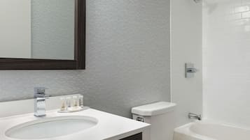 Een moderne badkamer met een wit wastafelmeubel, een spiegel, toilet en bad.
