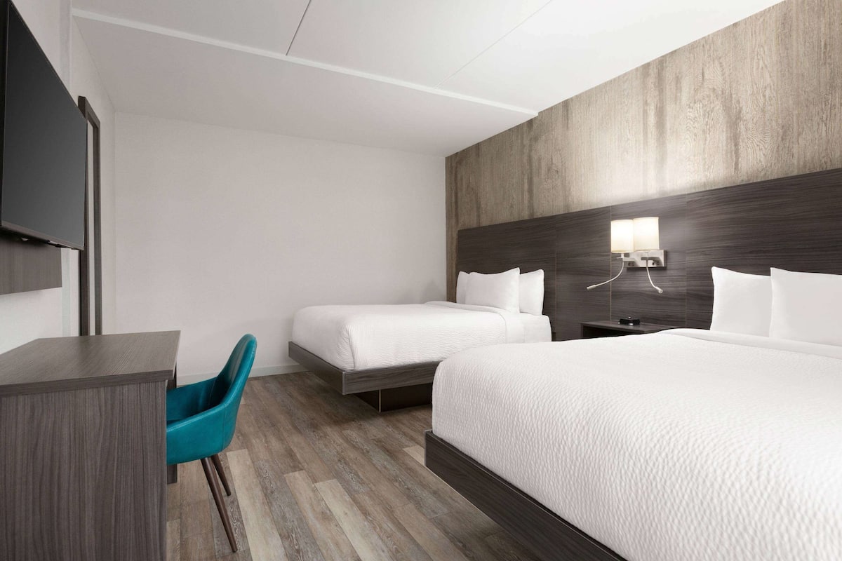 Ett modernt hotellrum med en stor säng, ett skrivbord och en stol.