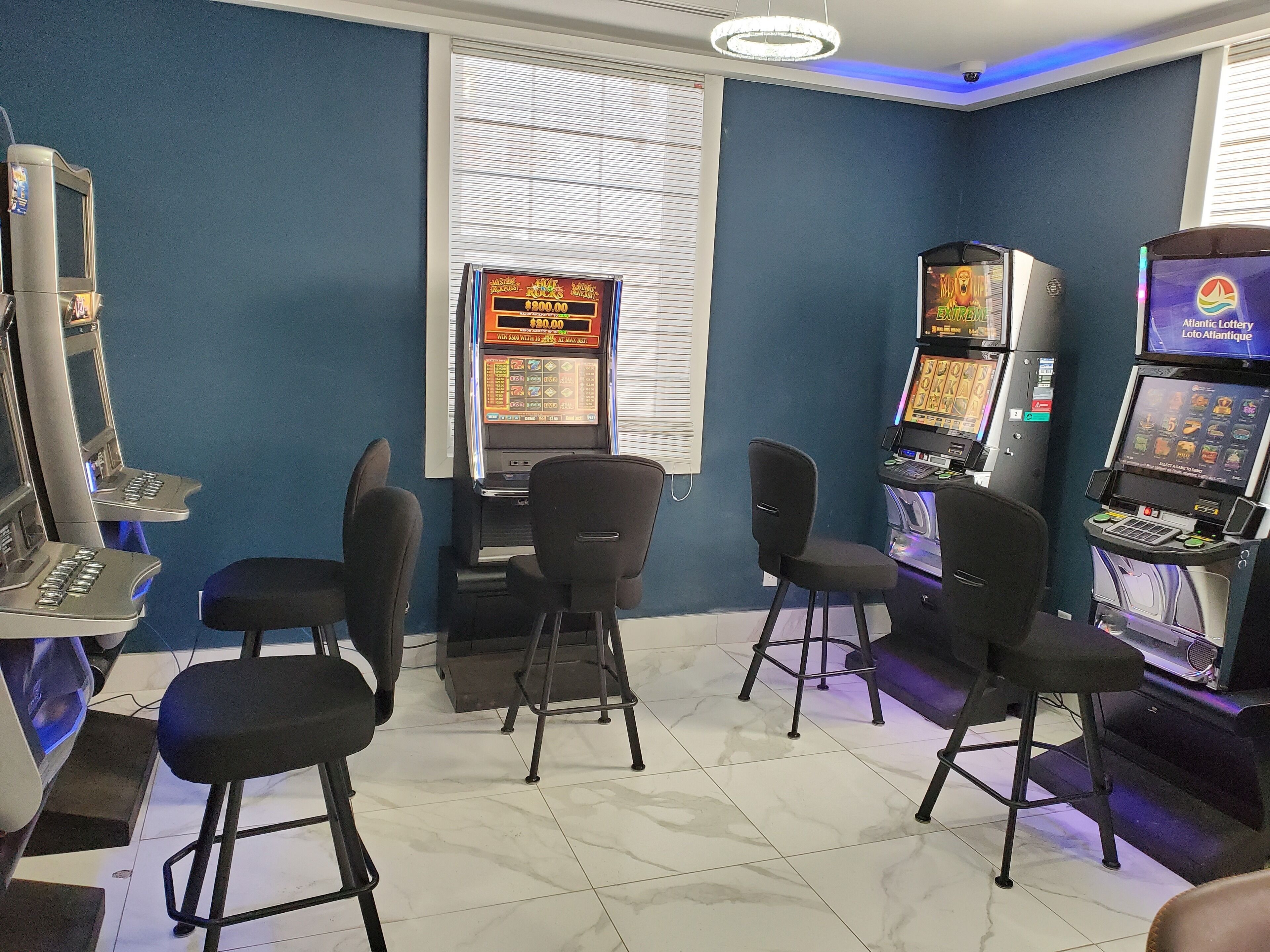 A room with gaming machines, black chairs, and a window with blinds.