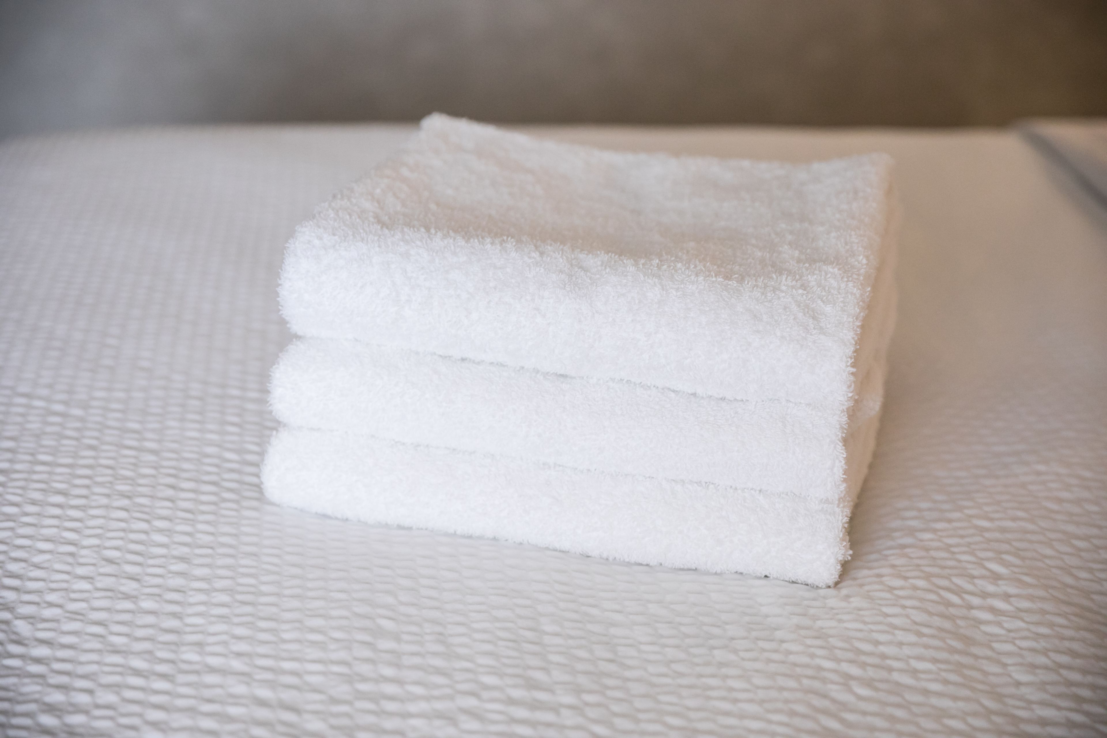 A stack of white towels on a textured white surface.