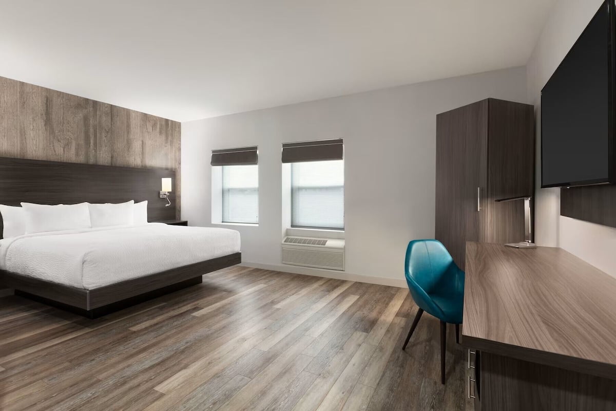 Ett modernt hotellrum med en stor säng, ett skrivbord och en TV.