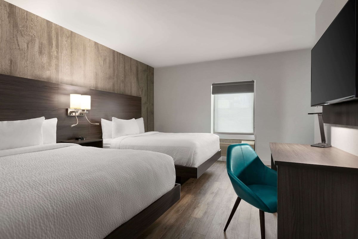 Ett hotellrum med två sängar, ett skrivbord, en stol och en TV.