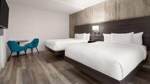 Ein Hotelzimmer mit zwei Betten, einem kleinen Tisch, zwei Stühlen und einem Fernseher.