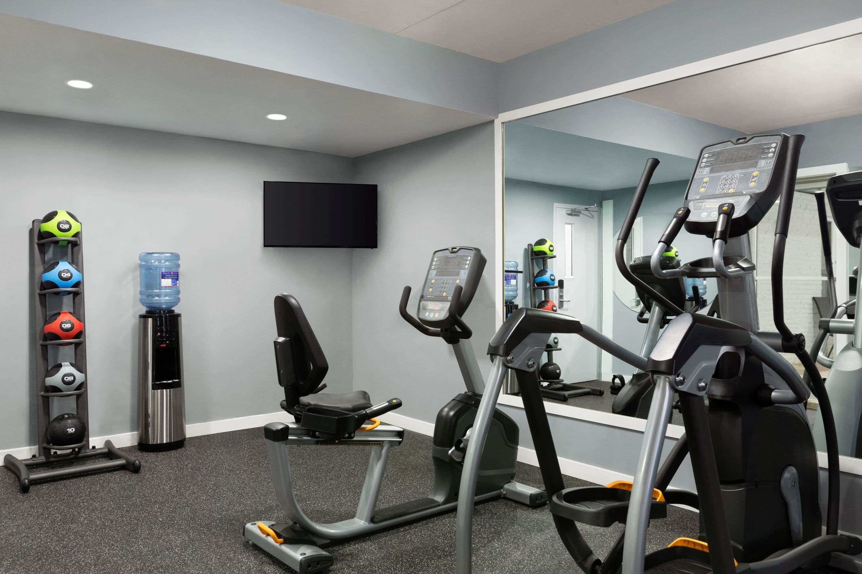 Une salle de sport équipée d’appareils de cardio, de machines de musculation et d’un distributeur d’eau.