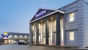 Ein Days Inn by Wyndham mit modernem Design, ein markantes Entree und ein Parkplatz mit mehreren Autos.