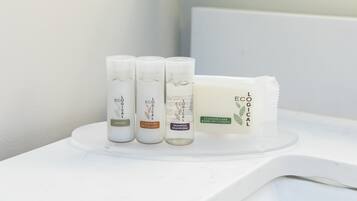 A bathroom with a white countertop displaying three bottles of L'ECOLYGE products and a bar of soap.