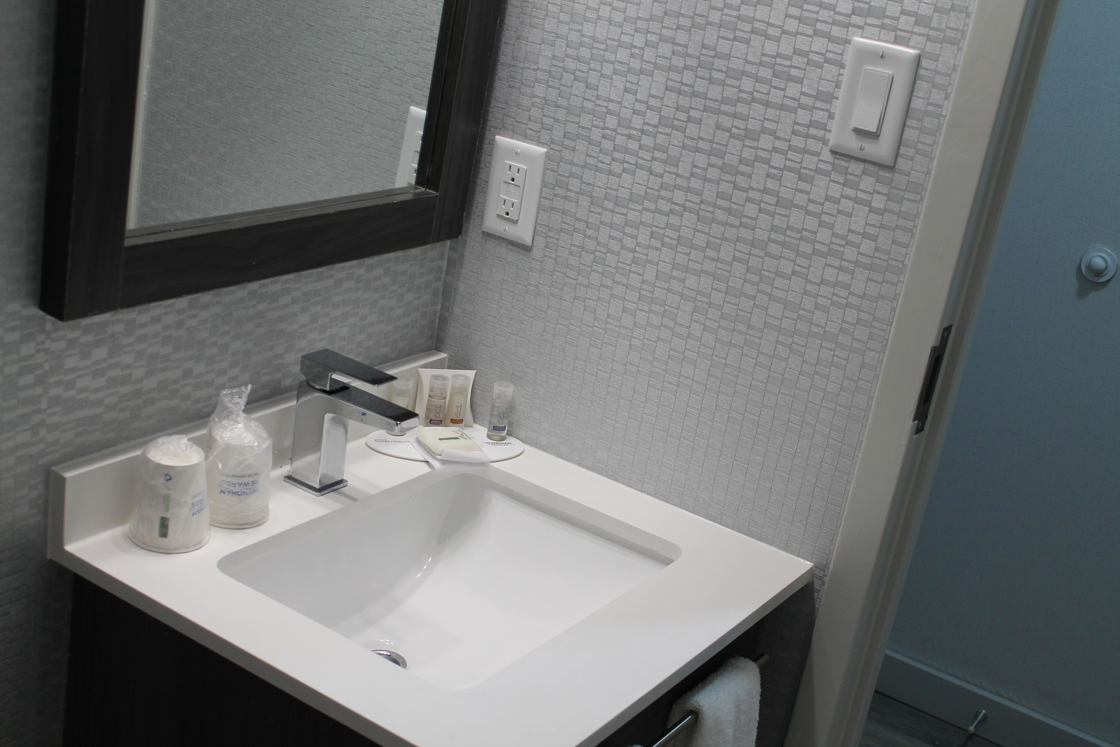 A bathroom with a white sink, a mirror, and toiletries.