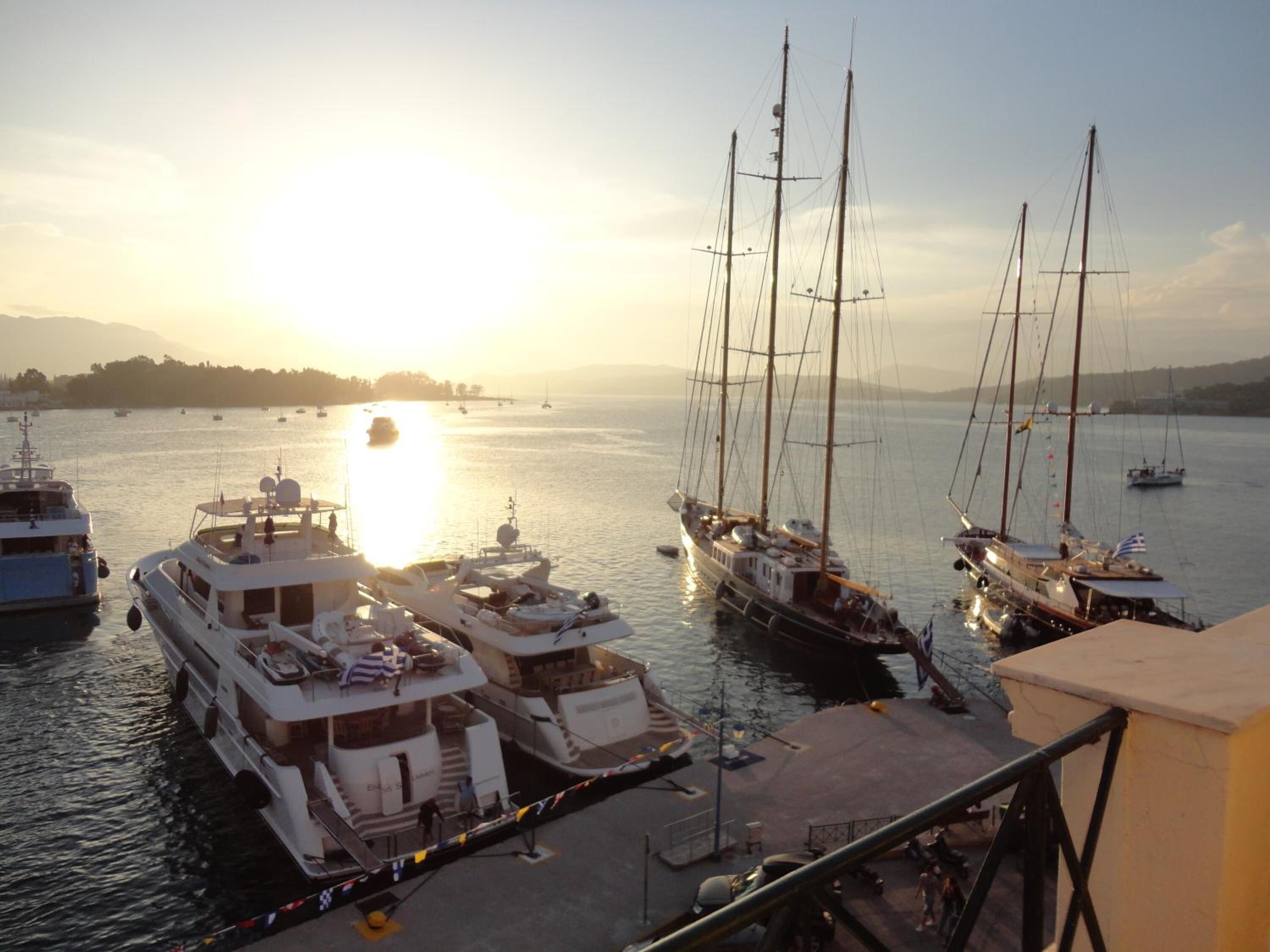 A marina with several boats docked, a clear sky, and a sunset in the background.
