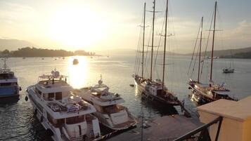 A marina with several boats docked, a clear sky, and a sunset in the background.