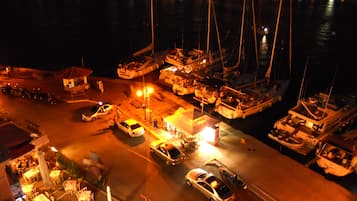 A marina at night with boats docked, a parking area, and a small building with a red roof.
