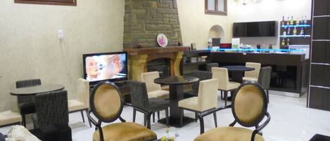 A modern living room with a stone fireplace, a television, and a bar area with shelves of bottles.