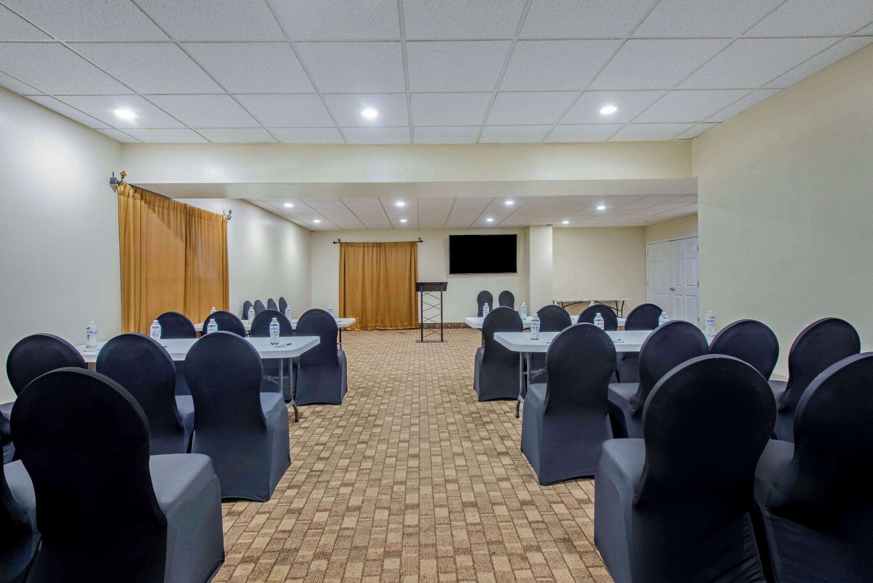 A conference room with tables and chairs, a projector screen, and a whiteboard.