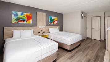 Camera d'albergo con due letti, una testiera in legno, un comodino e un quadro astratto appeso al muro.