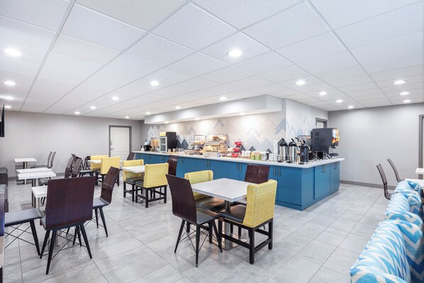 Un comedor moderno con una barra central, varias mesas y sillas.
