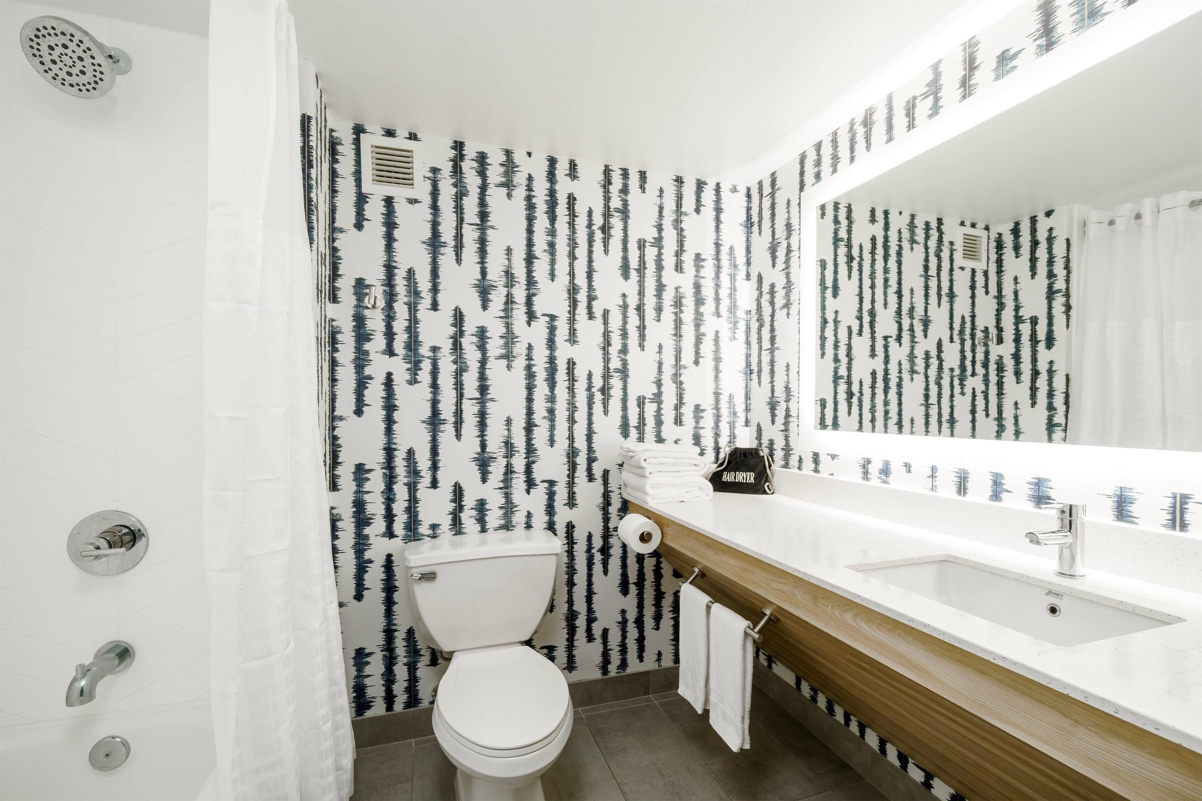 Une salle de bain avec des toilettes blanches, un meuble-lavabo en bois et un grand miroir.