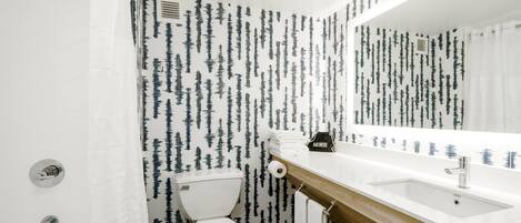 Une salle de bain avec des toilettes blanches, un meuble-lavabo en bois et un grand miroir.