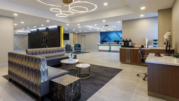 Un moderno vestíbulo de hotel con zonas de estar, un mostrador de recepción y una escalera.