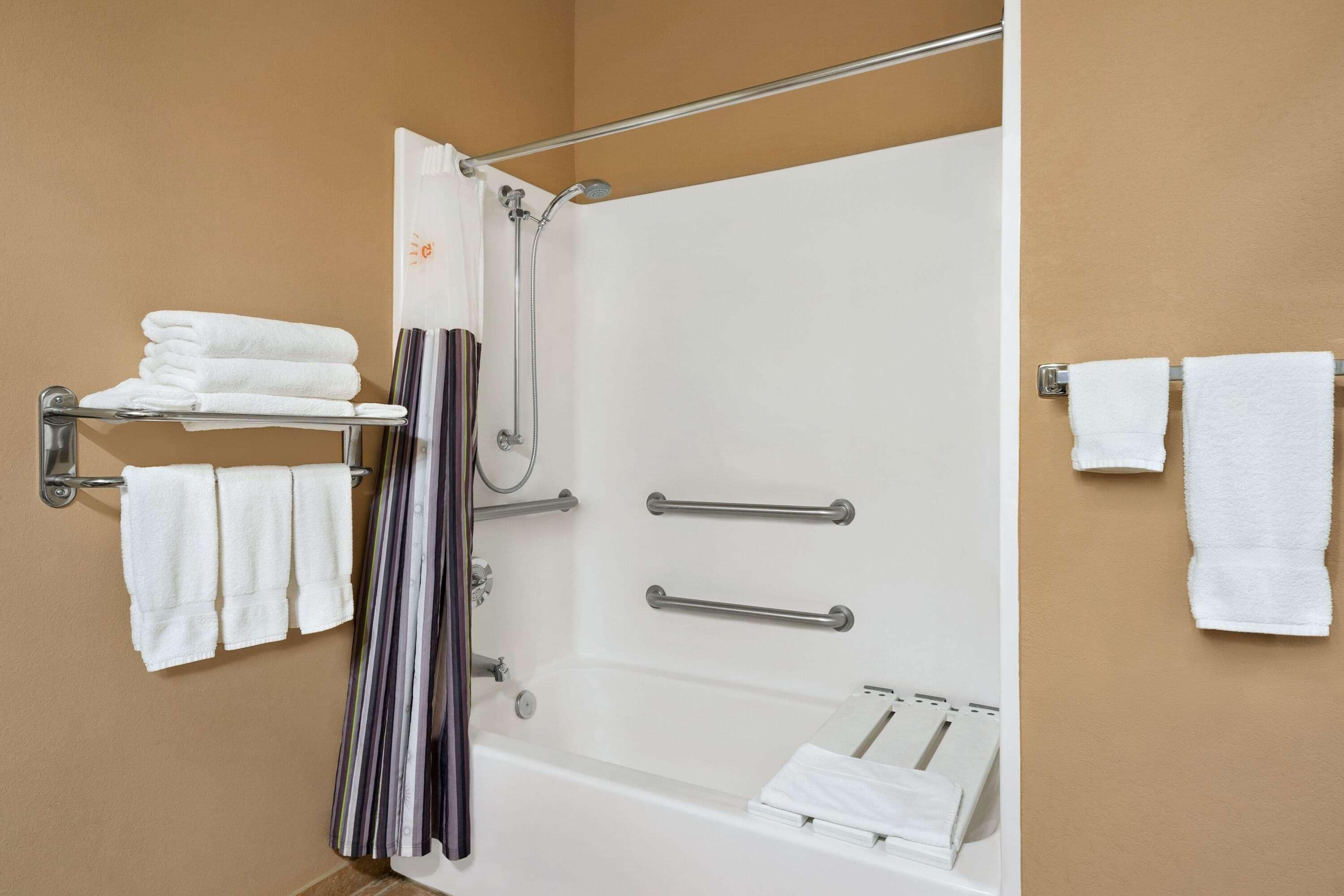 Une salle de bain équipée d’une baignoire, d’une douche et d’un porte-serviettes avec des serviettes pliées.