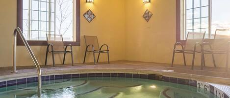Un espace piscine avec des chaises et une échelle, de grandes fenêtres et des lampes fixées au mur.