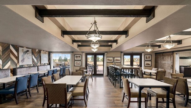 A spacious restaurant with high ceilings, exposed beams, and a central chandelier. Tables and chairs are arranged for dining. - La Quinta Inn & Suites by Wyndham Trinidad (Trinidad)