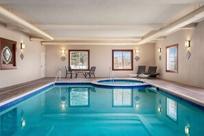 A large indoor swimming pool with a tiled edge, lounge chairs, and tables. - La Quinta Inn & Suites by Wyndham Trinidad (Trinidad)
